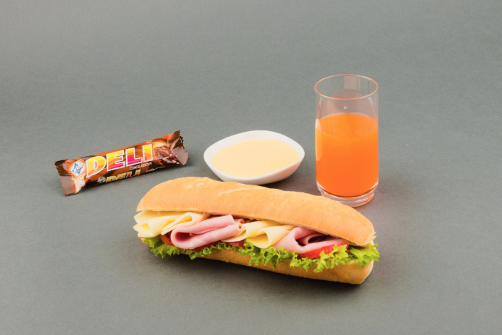 Cold children's meal - ham and cheese stuffed baguette, a chocolate stick, sweet curd, butter, apple juice, a white roll